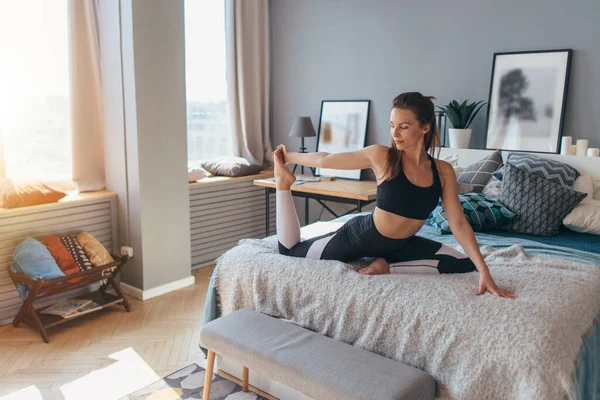 Fit mujer haciendo ejercicio en la cama en casa —  Fotos de Stock