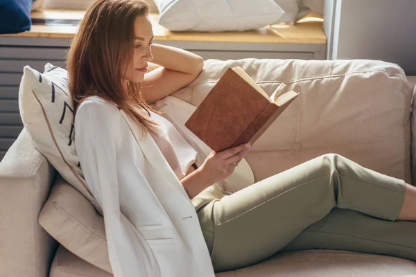 Γυναίκα ξεκουράζεται στο σπίτι και το διάβασμα του βιβλίου — Φωτογραφία Αρχείου