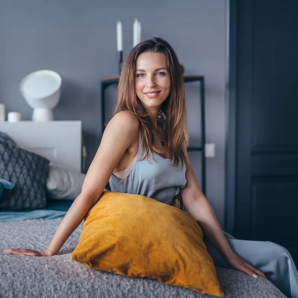Jeune belle femme assise sur le lit à la maison. — Photo
