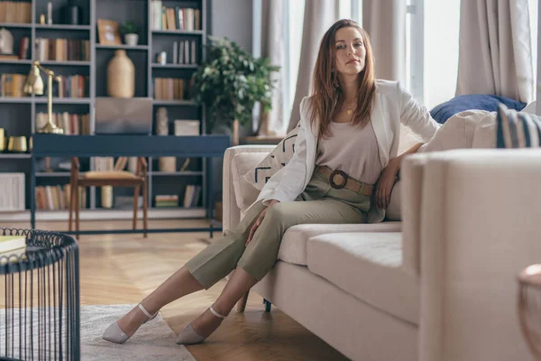 Frau in Businesskleidung nach Feierabend zu Hause auf Couch liegend. — Stockfoto