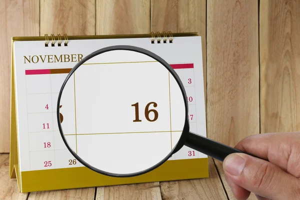Увеличительное стекло в руке на календаре вы можете посмотреть День шестнадцать — стоковое фото