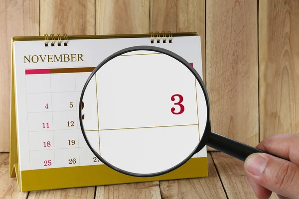 Увеличительное стекло в руке на календаре вы можете смотреть третий день м — стоковое фото