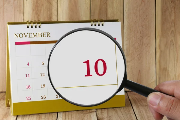Увеличительное стекло в руке на календаре вы можете посмотреть десятый день м — стоковое фото