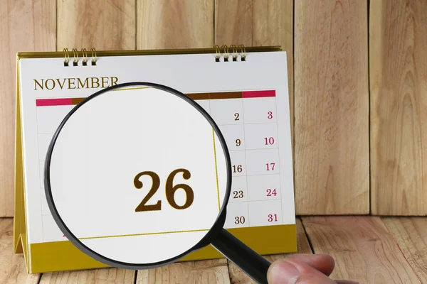 Увеличительное стекло в руке на календаре вы можете смотреть двадцать шесть дней — стоковое фото