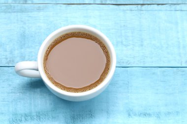 Mavi ahşap masa üzerinde beyaz bir kahve fincan sıcak kahve.