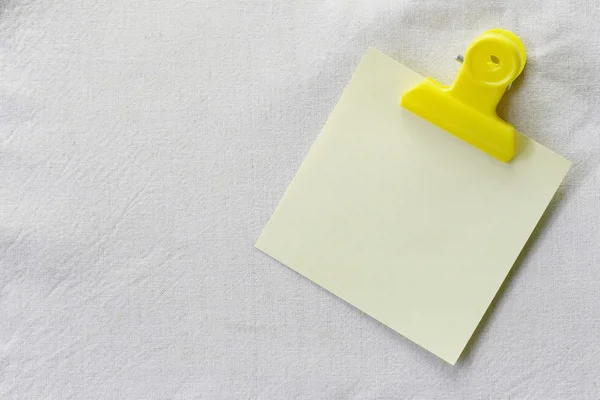 Sarı Not kağıt beyaz kumaş arka plan üzerine yerleştirilen. — Stok fotoğraf