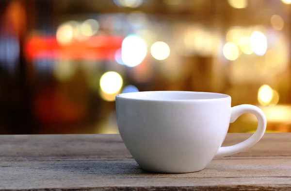 Taza de café blanco en la mesa de madera en la cafetería fondo borroso . — Foto de Stock