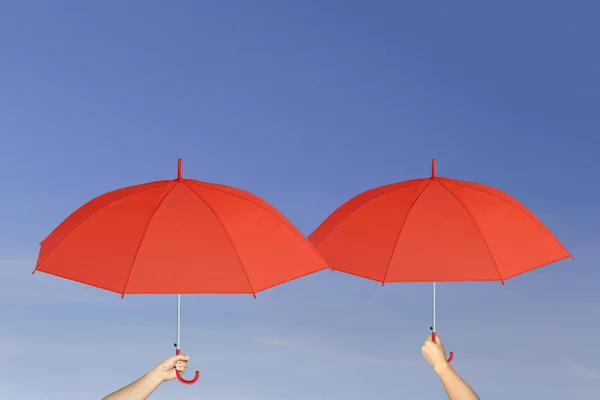 Parapluie rouge à la main sur fond bleu ciel . — Photo