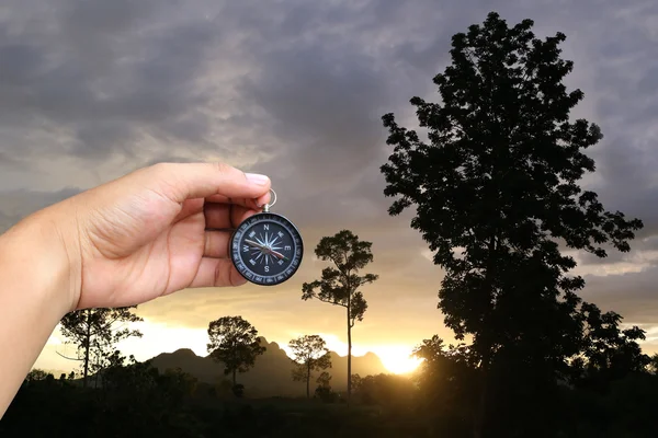 Tangan seorang pria memegang kompas di sore hari matahari terbenam di pedesaan — Stok Foto