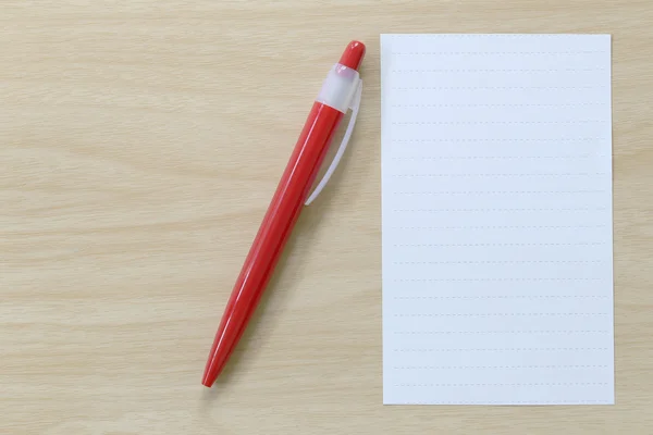 Papel de nota e caneta vermelha colocados no chão de madeira . — Fotografia de Stock