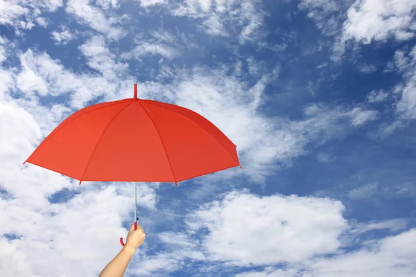 Red umbrella in hand on blue sky and cloud background. Royalty Free Stock Photos