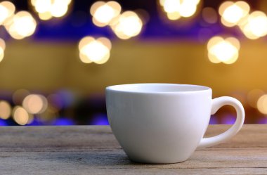Beyaz kahve fincanı kahve dükkanında ahşap masa üzerinde arka plan bulanıklık.