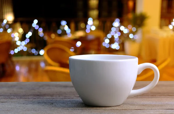Taza de café blanco en la mesa de madera en la cafetería fondo borroso . — Foto de Stock