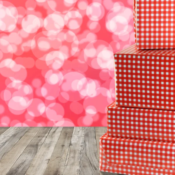 Červené dárkové boxy stohovat na dřevěné podlahy a bokeh červený abstrakt — Stock fotografie