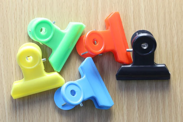 Clips de papel de plástico de colores en un suelo de madera . — Foto de Stock