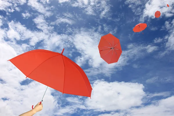 Красный зонтик в руке на голубом небе и фоне облаков . — стоковое фото