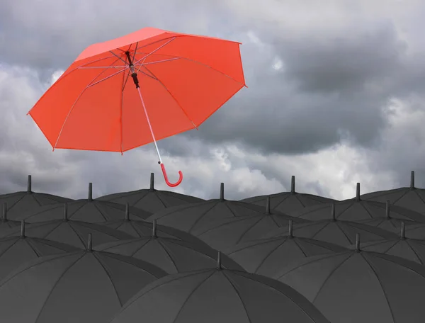 Paraguas rojo soplado por el viento y rodeado por un paraguas negro . — Foto de Stock