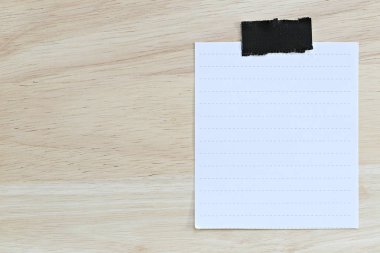 Beyaz kağıt boş veya kahverengi ahşap zemin üzerinde not kağıdı.