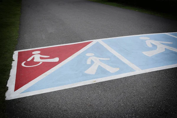 Camino de asfalto en el parque y tienen símbolo de las personas con discapacidad — Foto de Stock