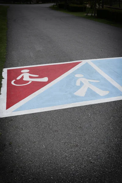 Estrada de asfalto no parque e tem símbolo de pessoas com deficiência — Fotografia de Stock