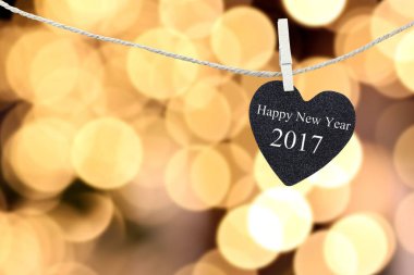 Black Heart bokeh altın renkli bir arka planla kenevir ipi üzerinde asılı