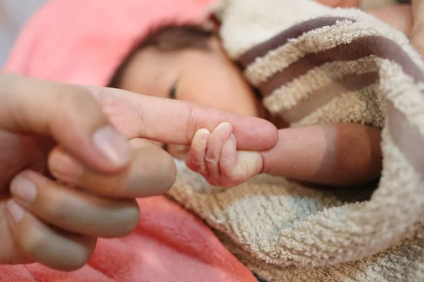 Hand von asiatischem Baby an Fingern der Mutter festgenommen. — Stockfoto