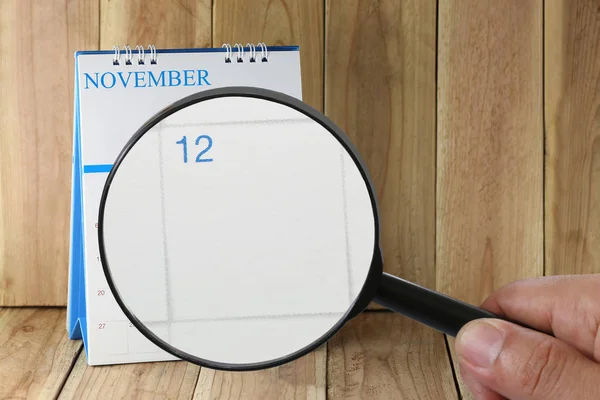 Увеличительное стекло в руке на календаре вы можете посмотреть двенадцатый день — стоковое фото