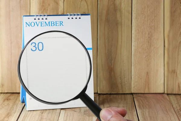 Увеличительное стекло в руке на календаре вы можете посмотреть тридцать дней — стоковое фото
