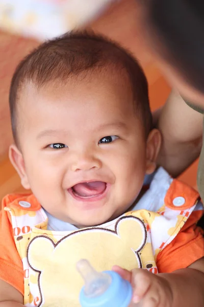 Asiático bebé sonriendo felizmente y tener botella de leche en la mano . —  Fotos de Stock