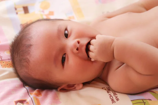 Азіатський Немовля, щасливо посміхаючись і рукою смоктати на ліжку. — стокове фото