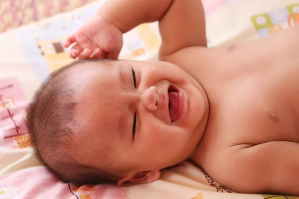 Asiatisches Baby weint auf dem Bett. — Stockfoto