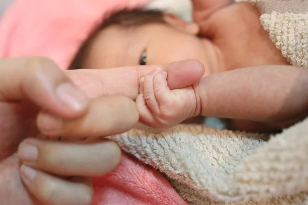 Hand von asiatischem Baby an Fingern der Mutter festgenommen. — Stockfoto