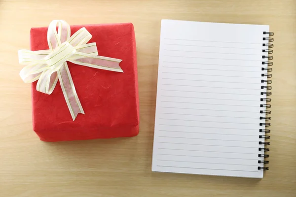 Libro vacío y caja de regalo roja en el suelo de madera . —  Fotos de Stock