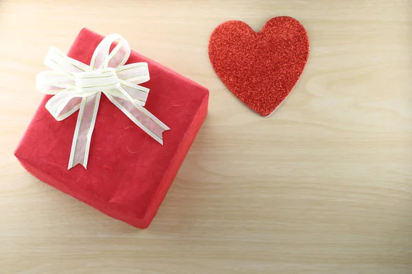 Libro vuoto e scatola regalo rossa posto vicino a forma di cuore sul legno — Foto Stock