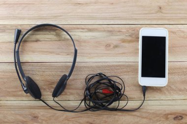 Devic kahverengi ahşap zemin ve kulaklık beyaz smartphone olduğunu