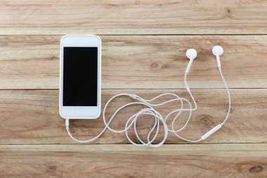 Devic kahverengi ahşap zemin ve kulaklık beyaz smartphone olduğunu