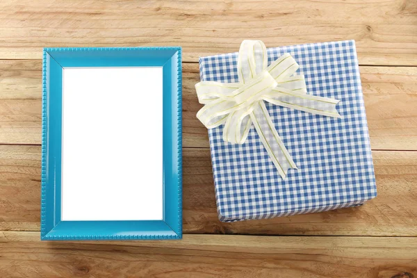 Lugar de caixa de presente azul perto de quadro de madeira azul no chão de madeira . — Fotografia de Stock