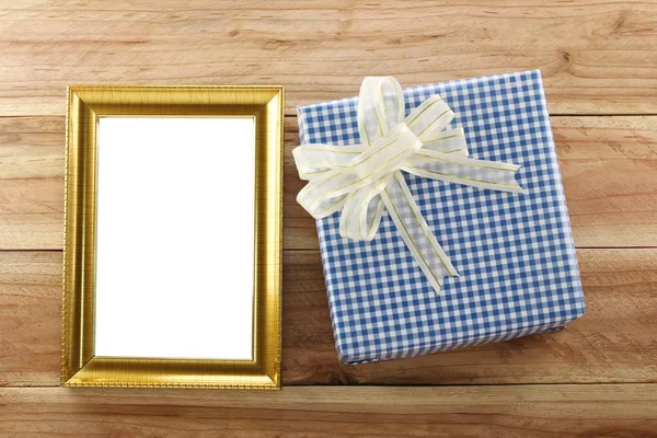 Caja de regalo azul lugar cerca de marco de madera de oro en el suelo de madera . —  Fotos de Stock