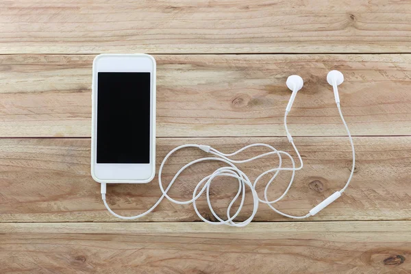 White smartphone on brown wood background and a headset is Devic — Stock Photo, Image