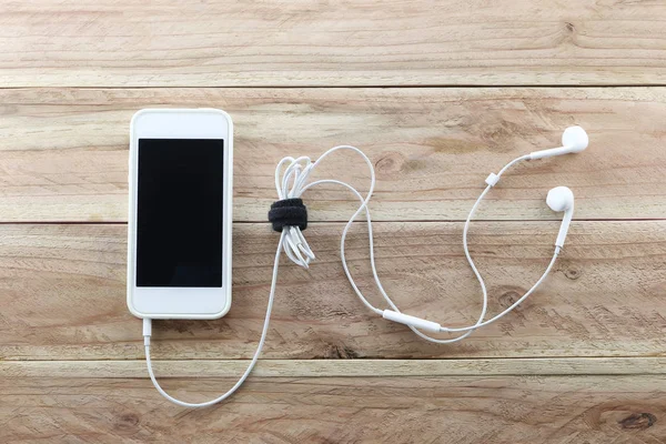 White smartphone on brown wood background and a headset is Devic — Stock Photo, Image