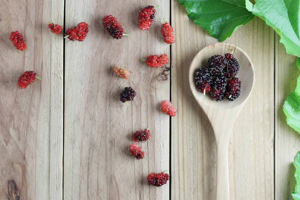 Fruit van de moerbei op houten lepel en groene bladeren op hout CHTERGRO — Stockfoto