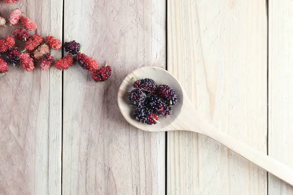 Mulberry frukt i trä sked på trä bakgrund. — Stockfoto