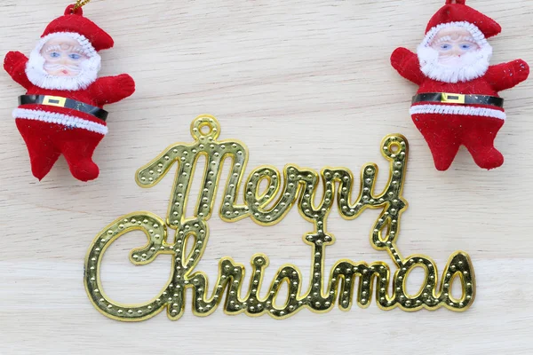 Texto de oro de Feliz Navidad y muñeca de Santa Claus en la espalda de madera — Foto de Stock
