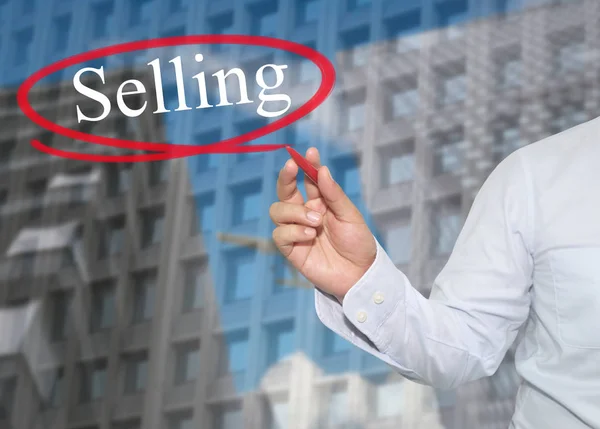 Hand eines jungen Geschäftsmannes schreibt das Wort Verkauf auf Wolkenkratzern — Stockfoto