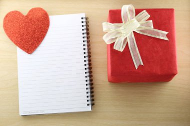 Boş kitap ve ahşap zemin üzerinde kırmızı hediye kutusu.