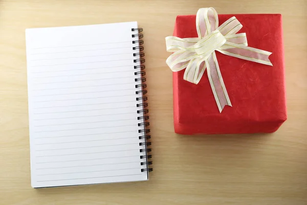 Libro vacío y caja de regalo roja en el suelo de madera . —  Fotos de Stock