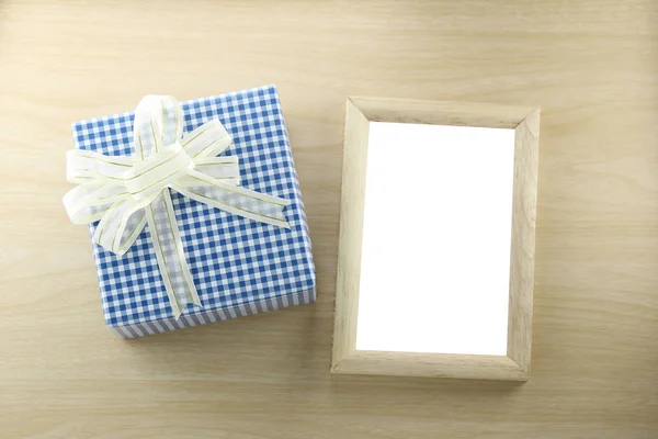 Caja de regalo azul lugar cerca de marco de madera en el suelo de madera . —  Fotos de Stock