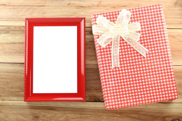 Red gift box with empty wooden picture frame on wood background. — Stock Photo, Image