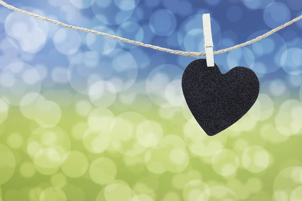Black Heart hung on hemp rope on abstract colorful bokeh backgro — Stock Photo, Image