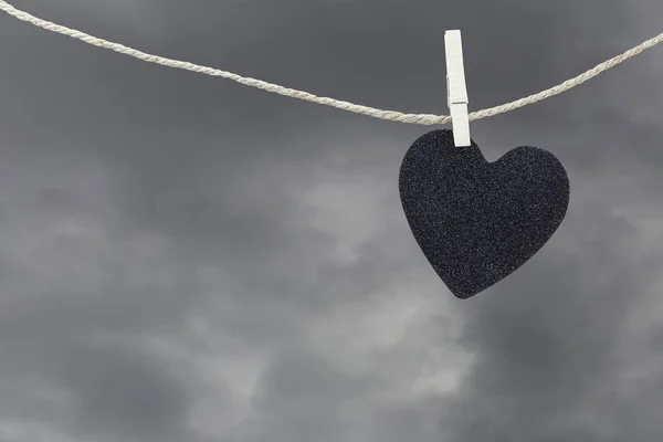 Czarne serce papieru wiszące na sznurku brąz konopi na deszcz chmury ba — Zdjęcie stockowe